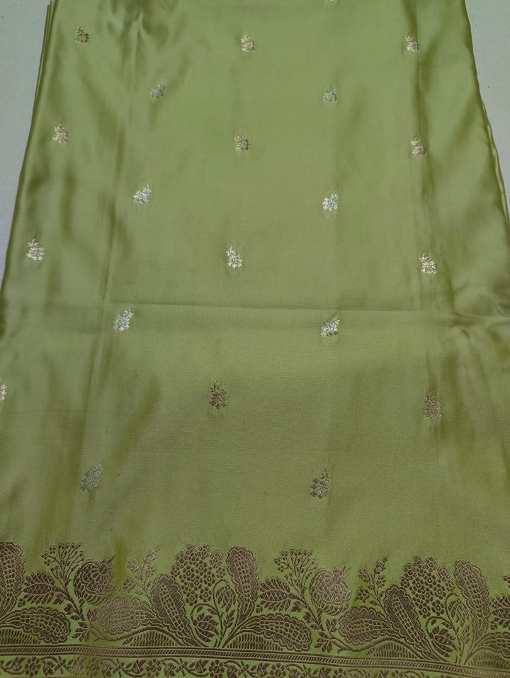 Green fabric with intricate gold embroidery on a plain background