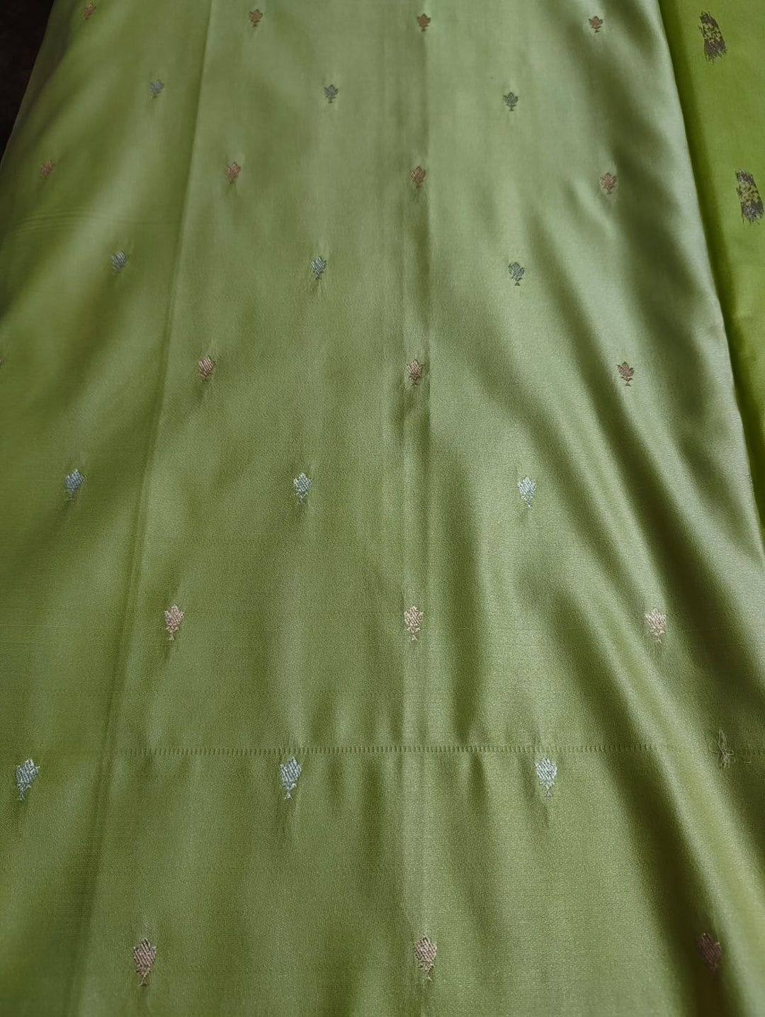 Close-up of green fabric with small embroidered patterns