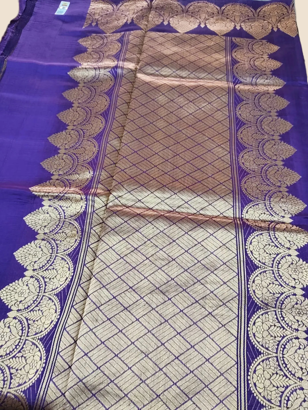 Purple saree with gold and white patterns on a plain background