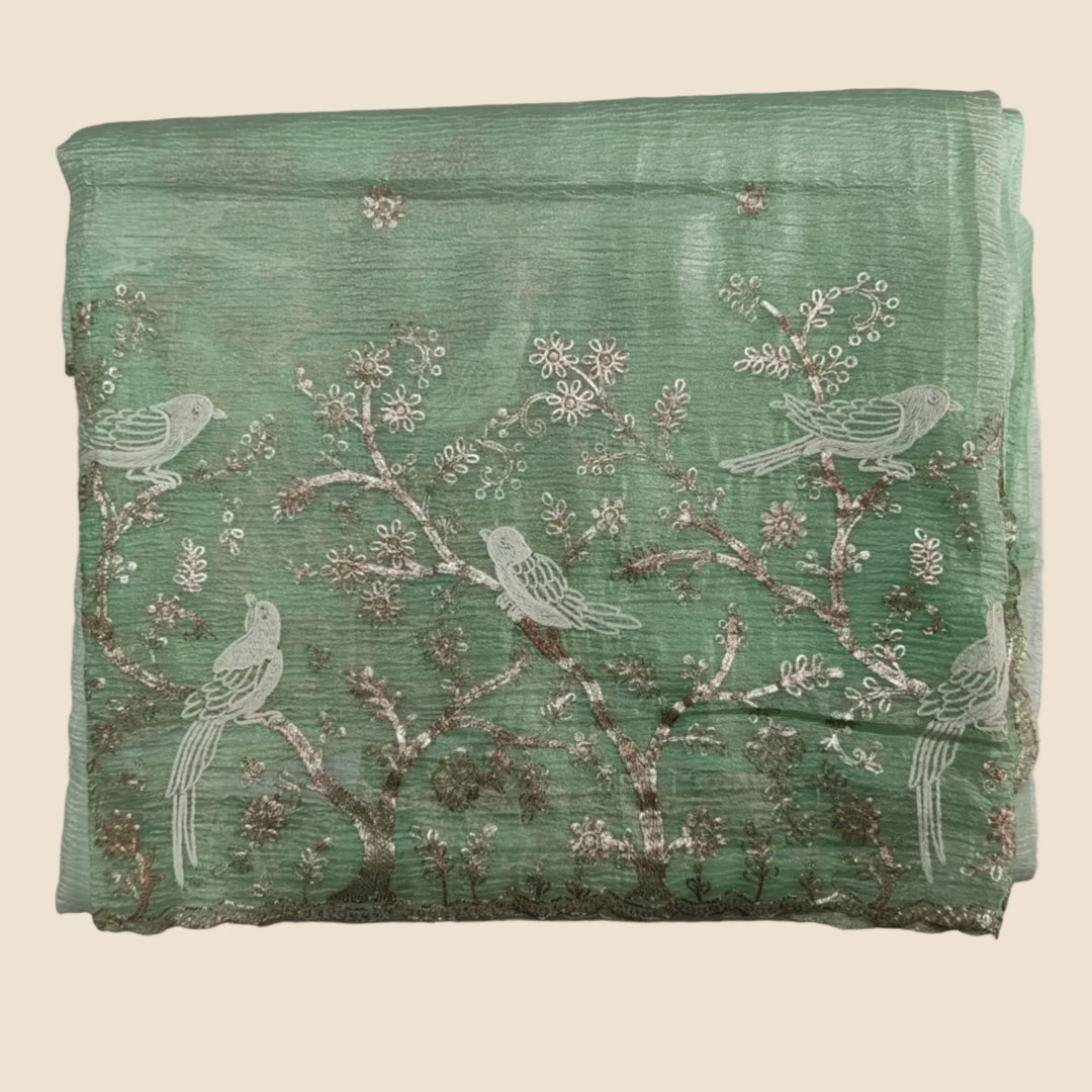 Green fabric with bird and floral patterns on a white background