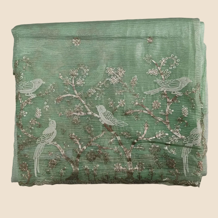 Green fabric with bird and floral patterns on a white background