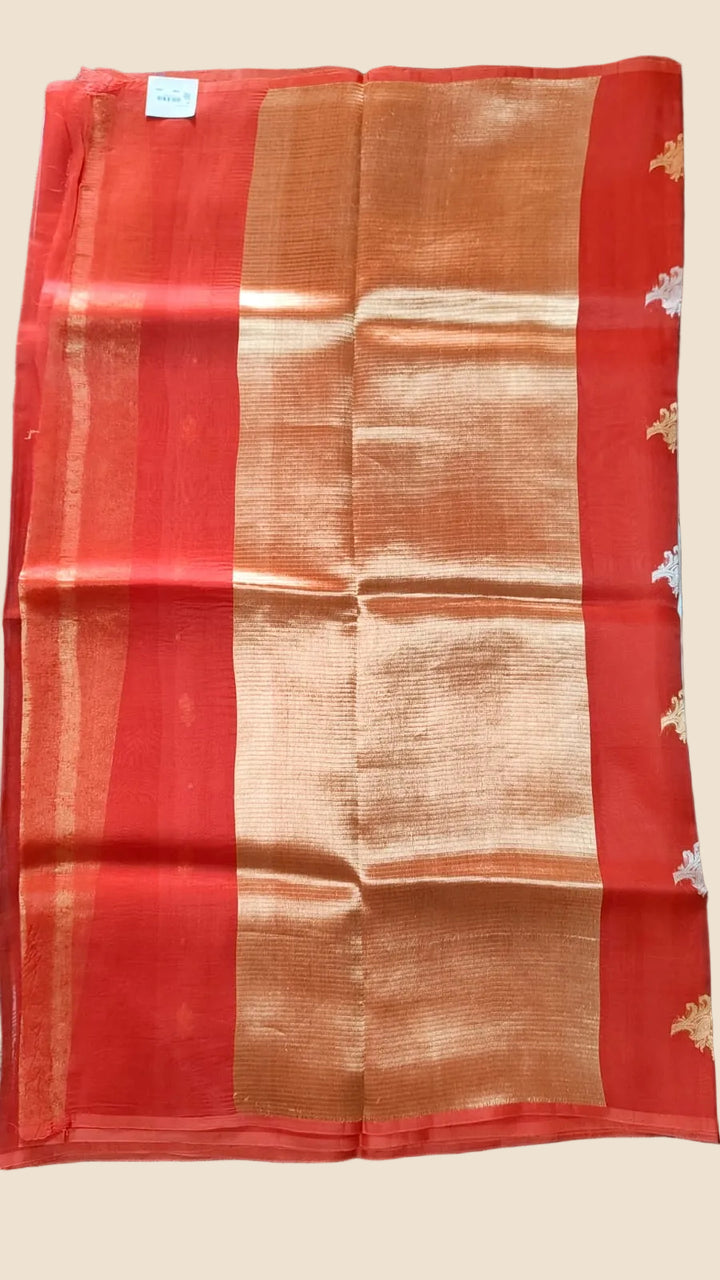 Red and gold saree with a visible brand label on a dark textured surface