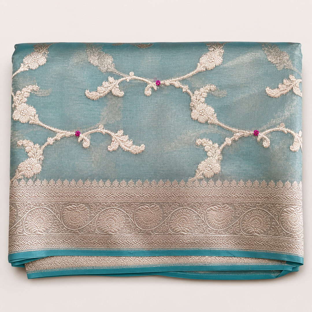 Folded fabric with intricate silver embroidery on a light blue background