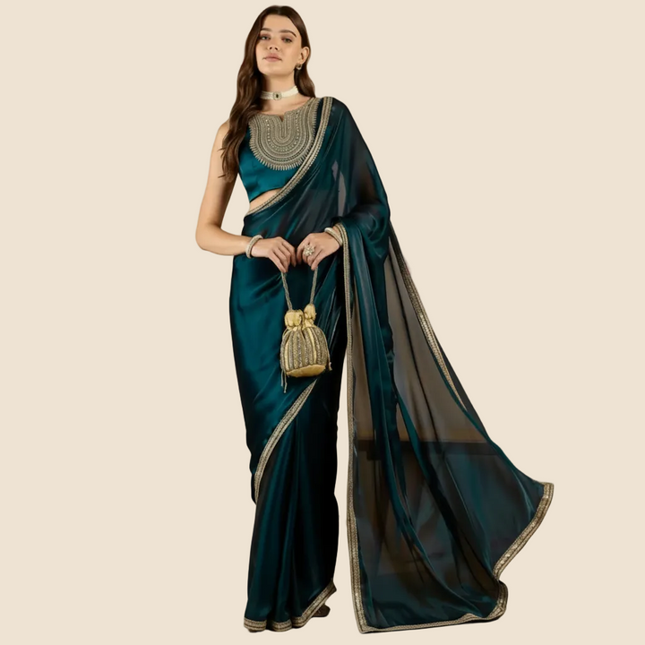 Woman wearing a teal saree with gold details against a beige background