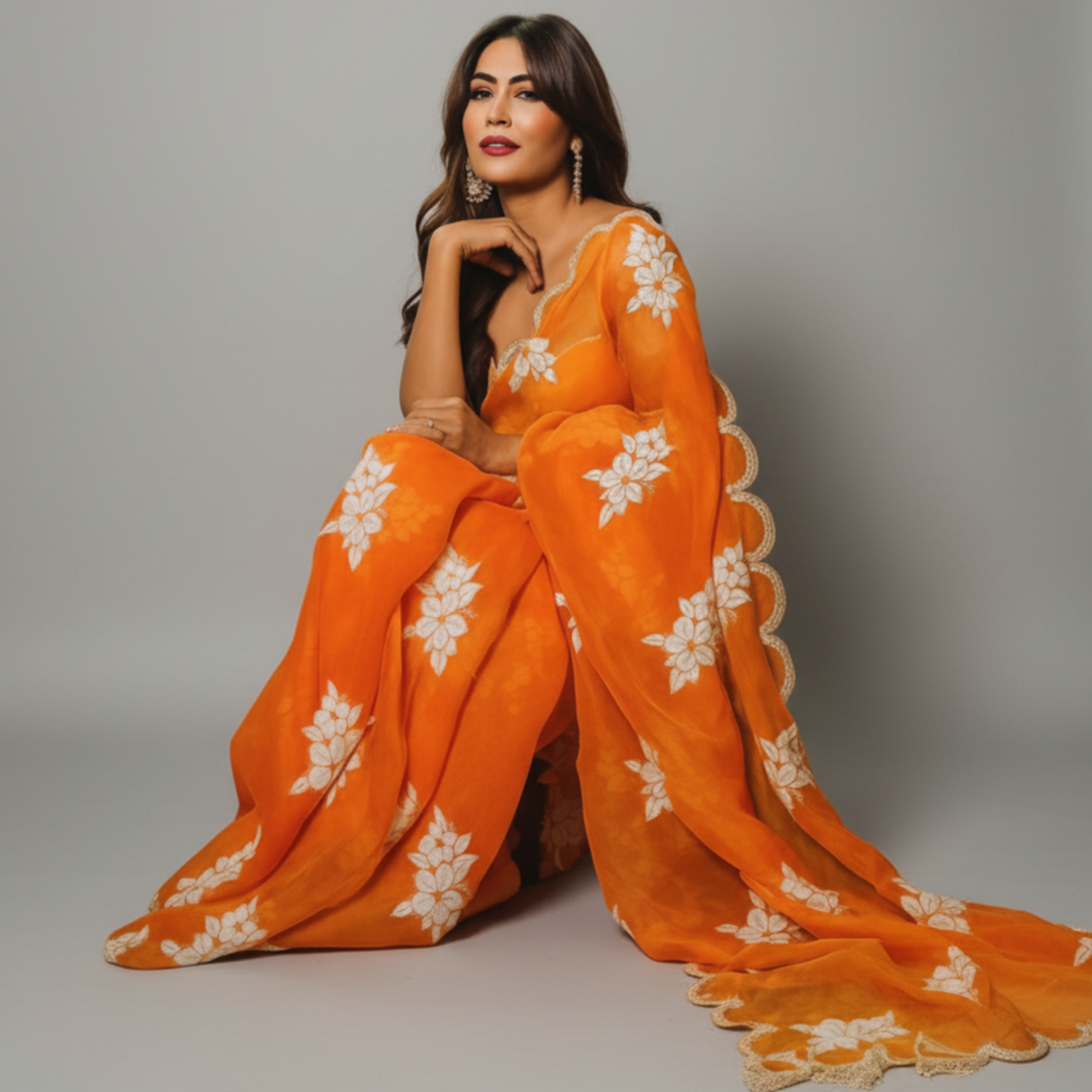 Woman in an orange saree with white patterns
